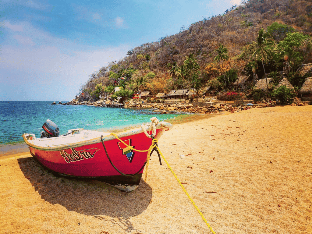 A red boat moored on a sandby beach.