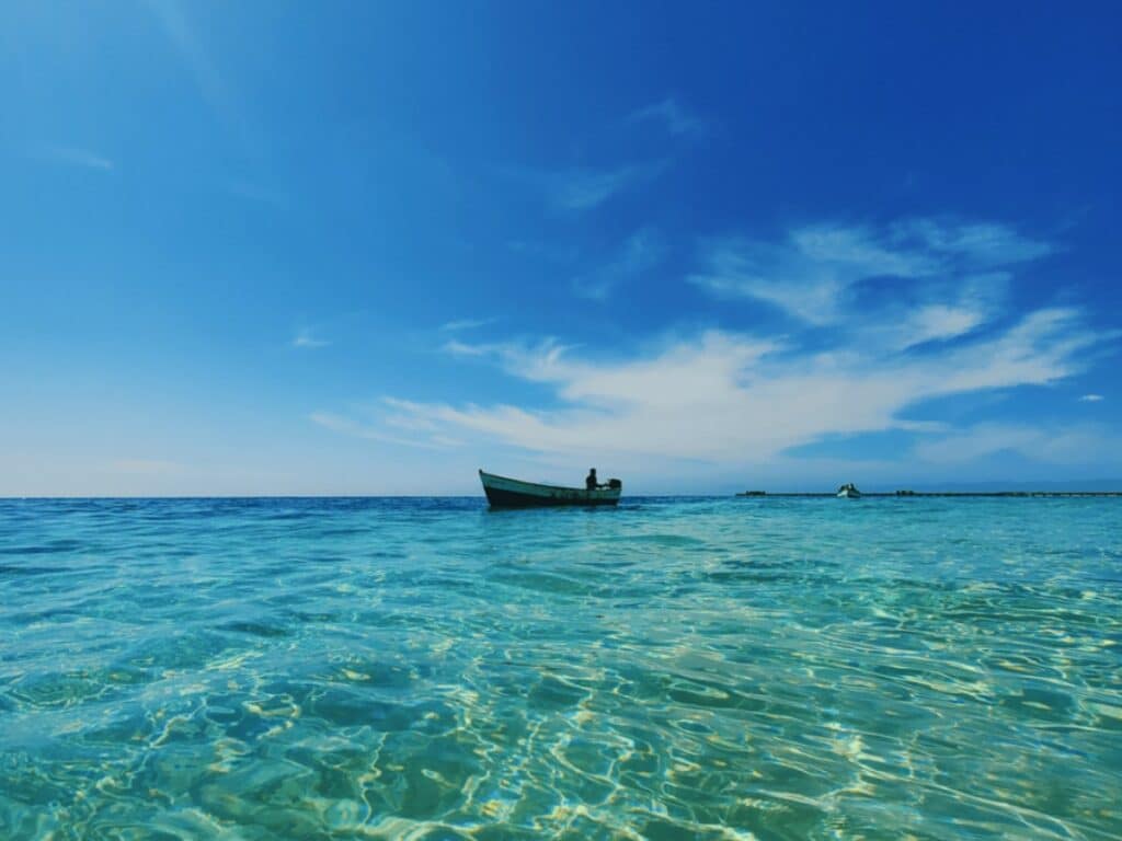 Small island country: a single boat alone on a wide, wide sea. And a beautiful sea at that.